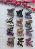 Collection of butterfly-shaped earrings on a white surface with pink flowers and leaves.