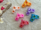 Floral blossom hair claw clips with glossy finish arranged on a soft background
