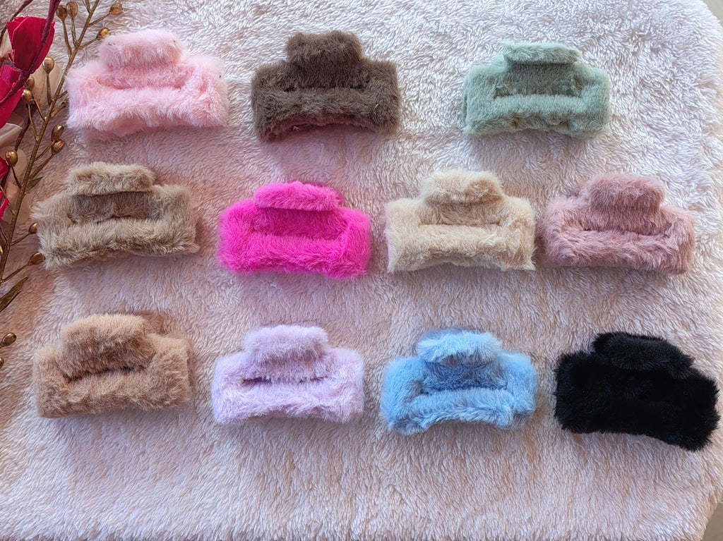 Assorted colorful fuzzy hair clips on a textured surface